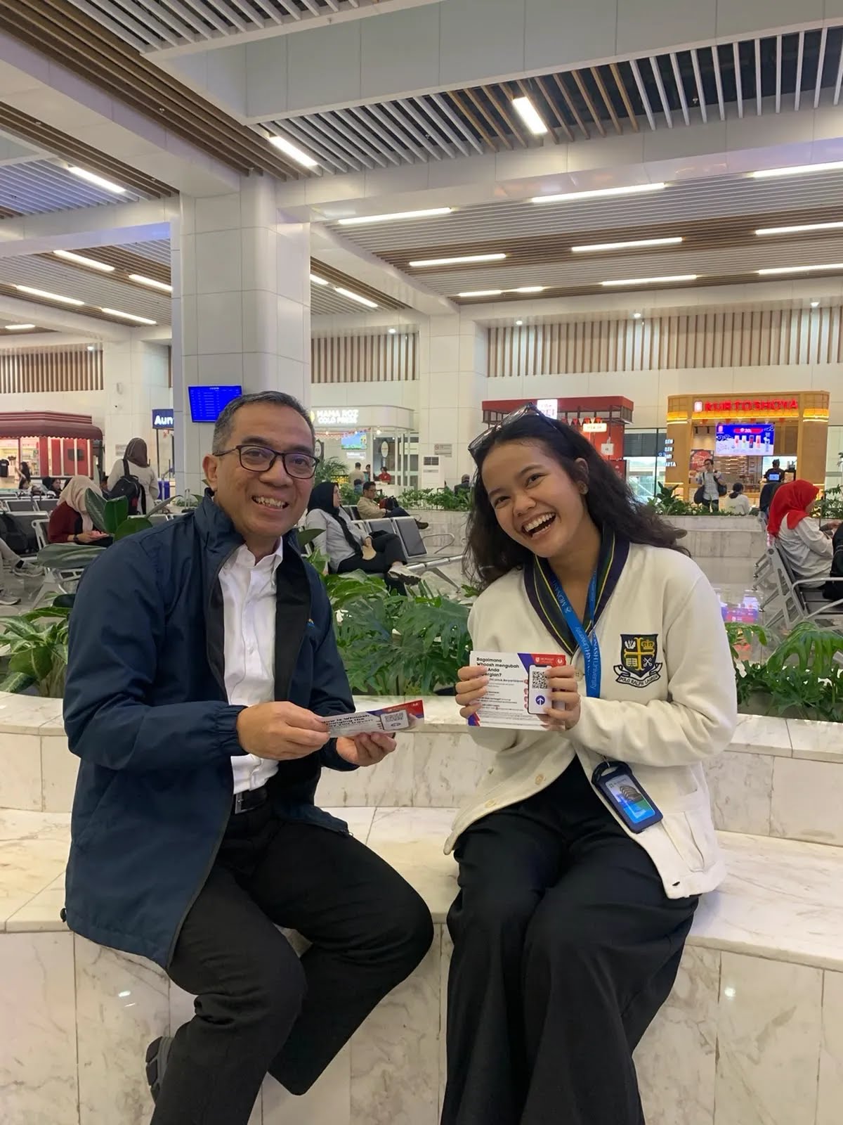 Indonesia's Minister of Higher Education, Science and Technology with a Monash researcher, both holding Whoosh passenger survey flyers at Halim HSR Station