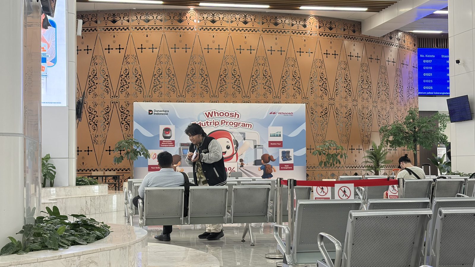 A survey team member distributing flyers in the departure hall at Halim HSR Station